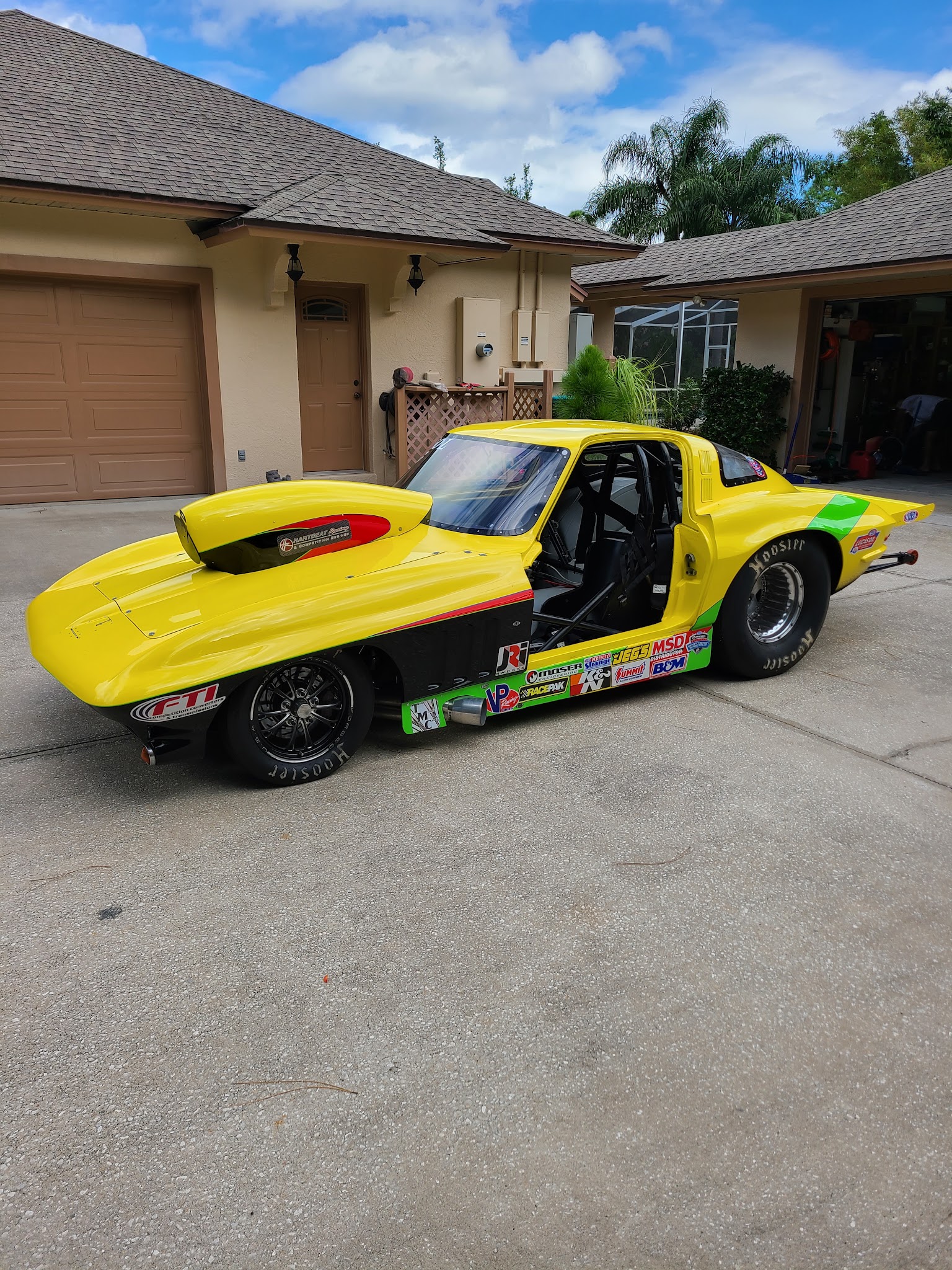 Yellow Corvette drag car with roll cage, Hoosier slicks, and racing sponsor decals