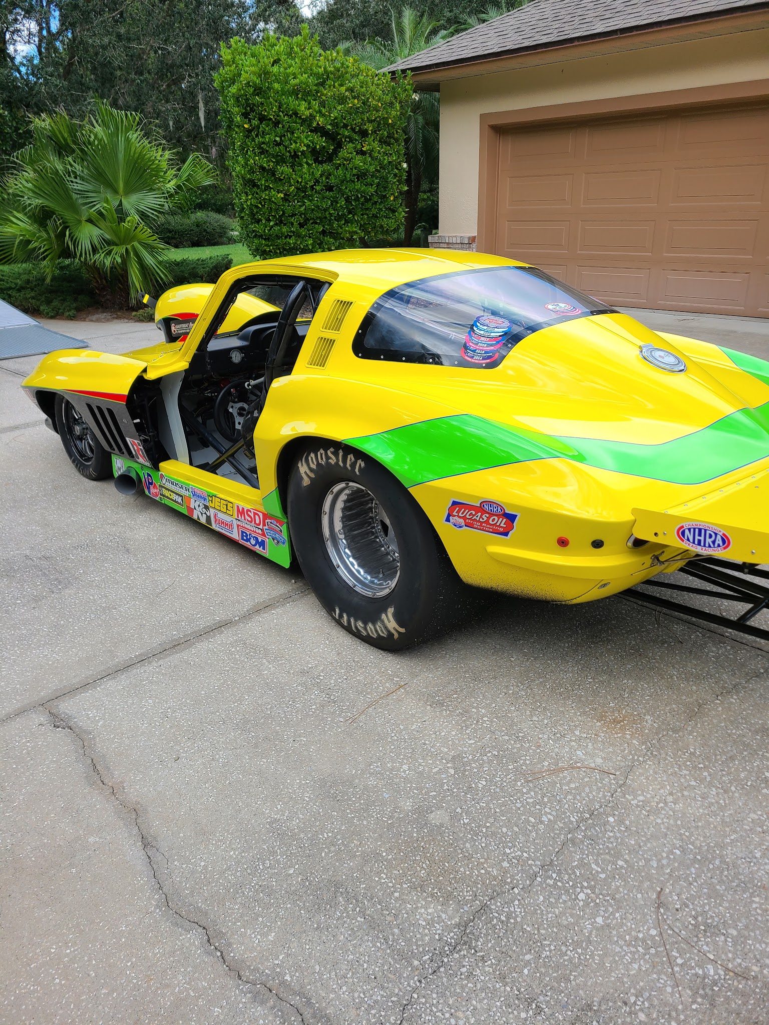 Yellow and green Corvette drag car rear view with NHRA stickers and Hoosier drag slicks