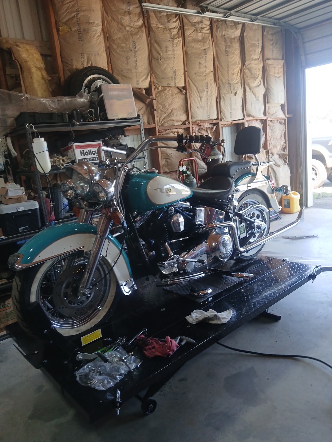 Teal and white Harley-Davidson Heritage Softail on the motorcycle lift being serviced
