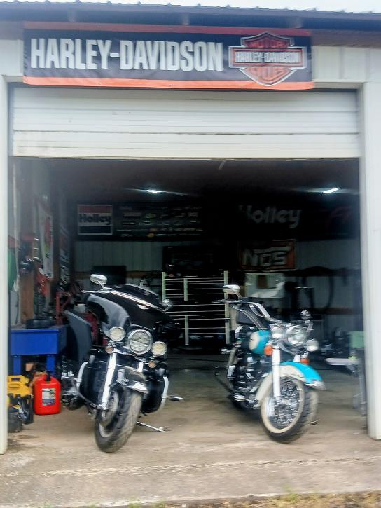Shop bay entrance with two Harley-Davidson motorcycles and Harley-Davidson banner overhead